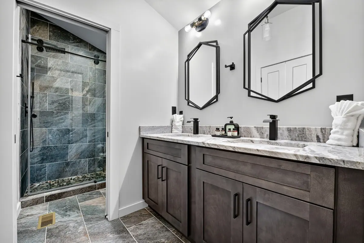 Bathroom with a double marble-topped vanity, dark wood cabinetry and matte black fixtures.