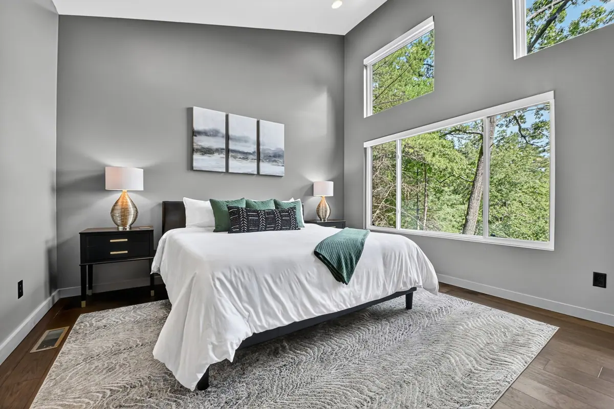 Second king suite with neutral bedding and windows looking into the forest canopy.