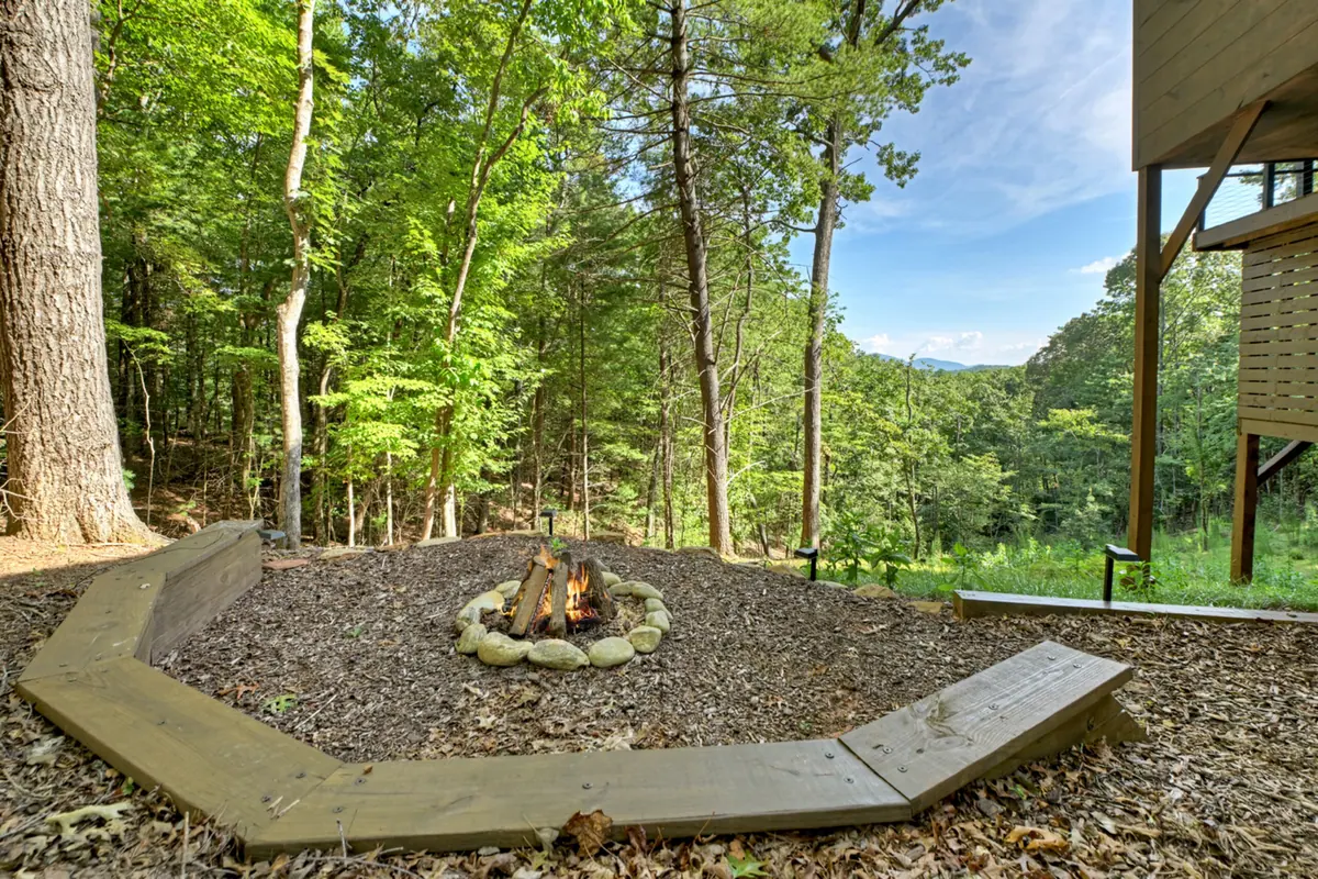 Stone-ringed fire pit in a clearing beside the cabin, surrounded by woodland.