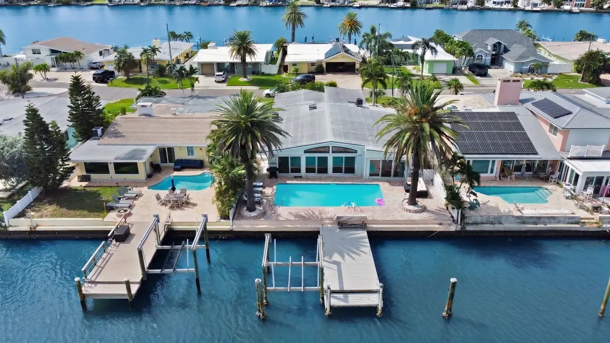 Aerial view of the house, pool and dock on the waterfront cove, with neighbouring homes along the shoreline.
