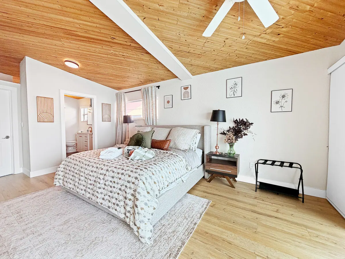 Guest bedroom in warm neutrals with a bench at the end of the bed and framed prints above.