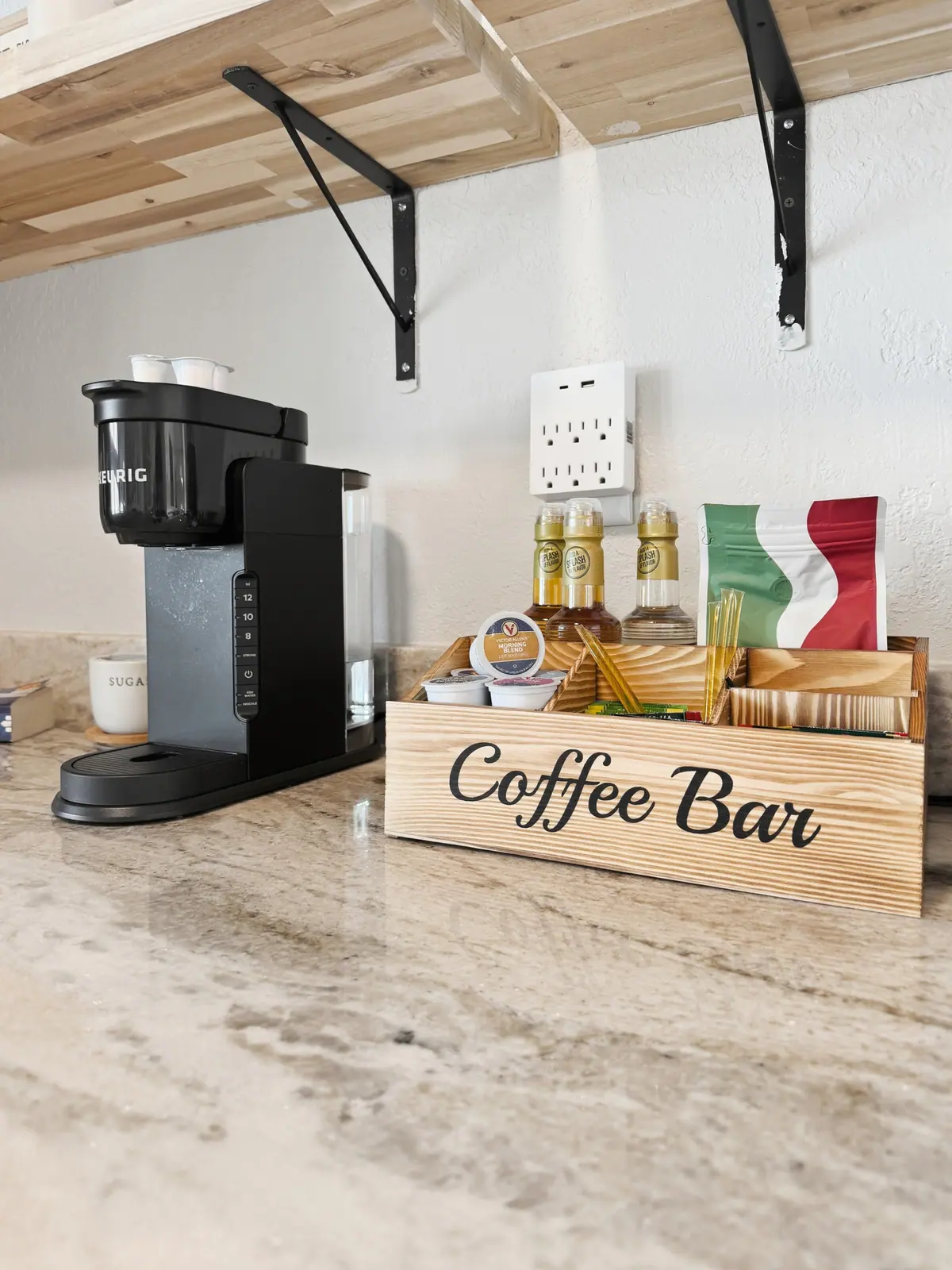 Coffee bar with a Keurig machine, a wooden Coffee Bar sign and a tray of syrups.