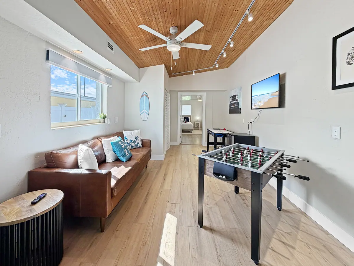 Games area with a foosball table beside a leather sofa on pale timber flooring.