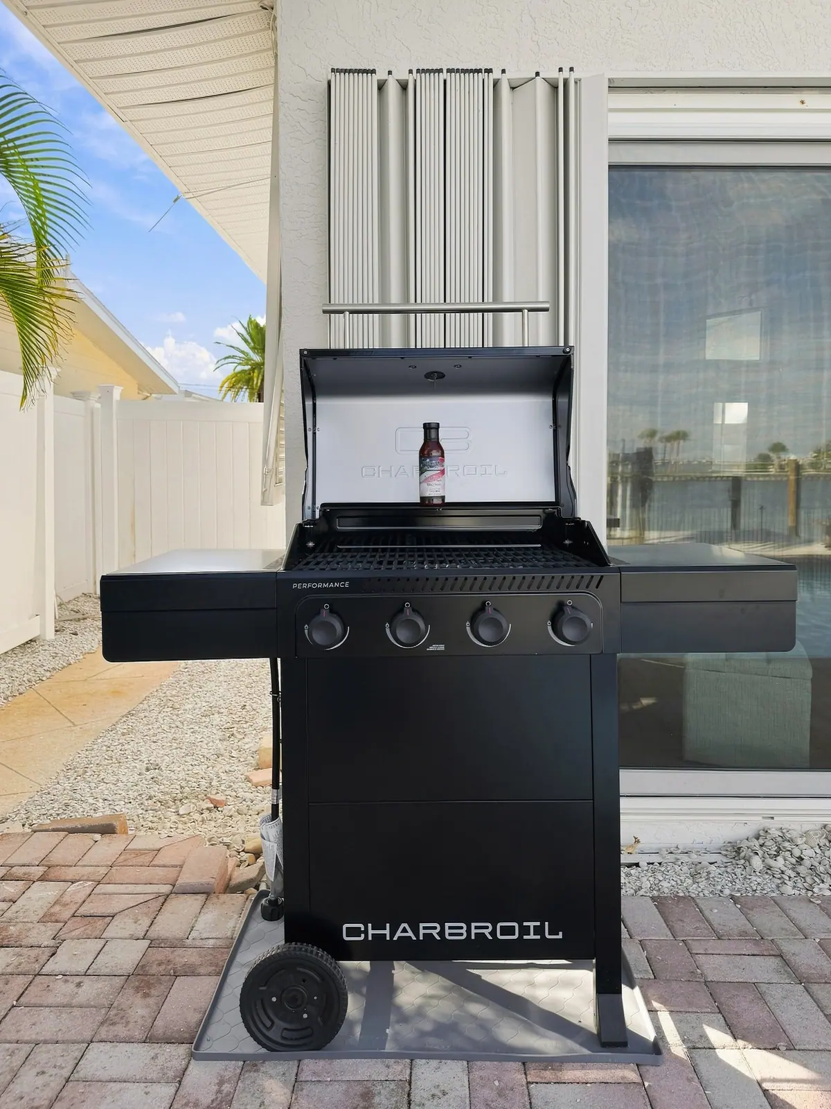 Gas barbecue on the paver patio beside the pool fence.