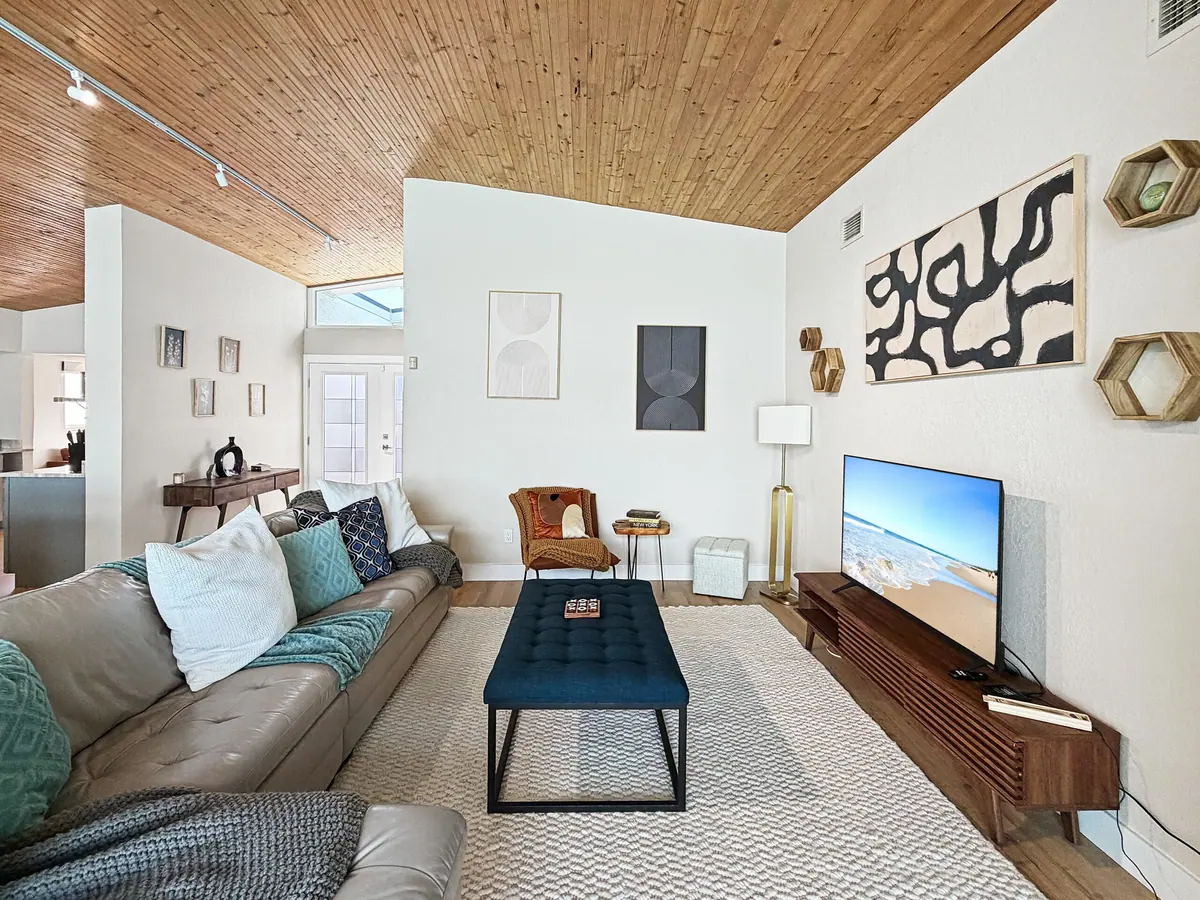 Living room with a deep sectional, mounted television and a wall of windows facing the water.