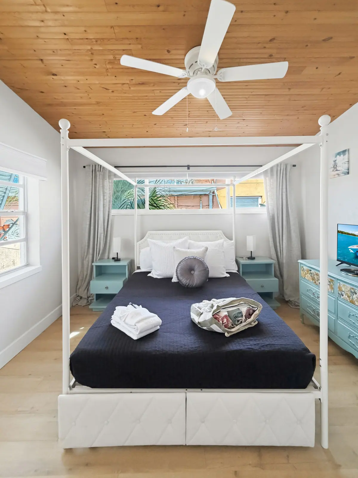 Primary bedroom with a four-poster bed, navy bedding and rolled towels laid out at the foot.