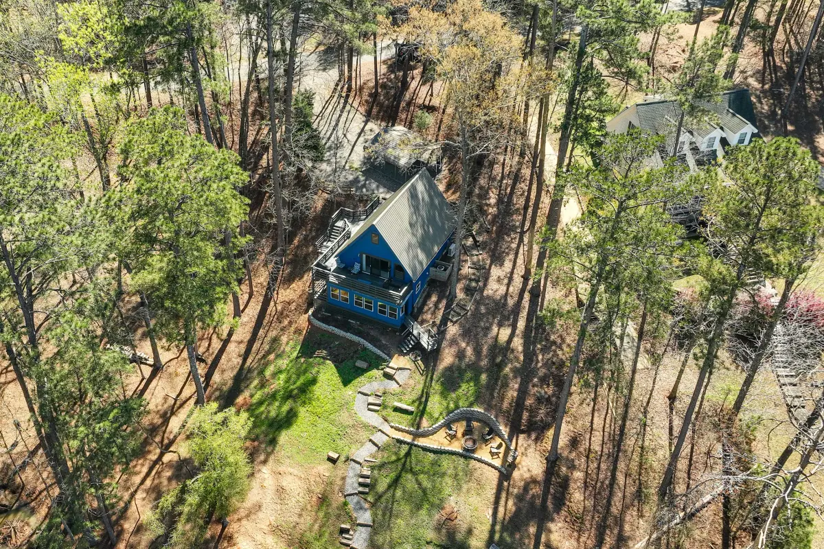 Aerial view of the A-frame cabin among the pines with its lake frontage below.
