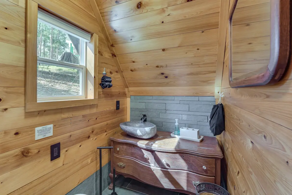 Bathroom with a vessel sink set into a timber vanity against pine-panelled walls.