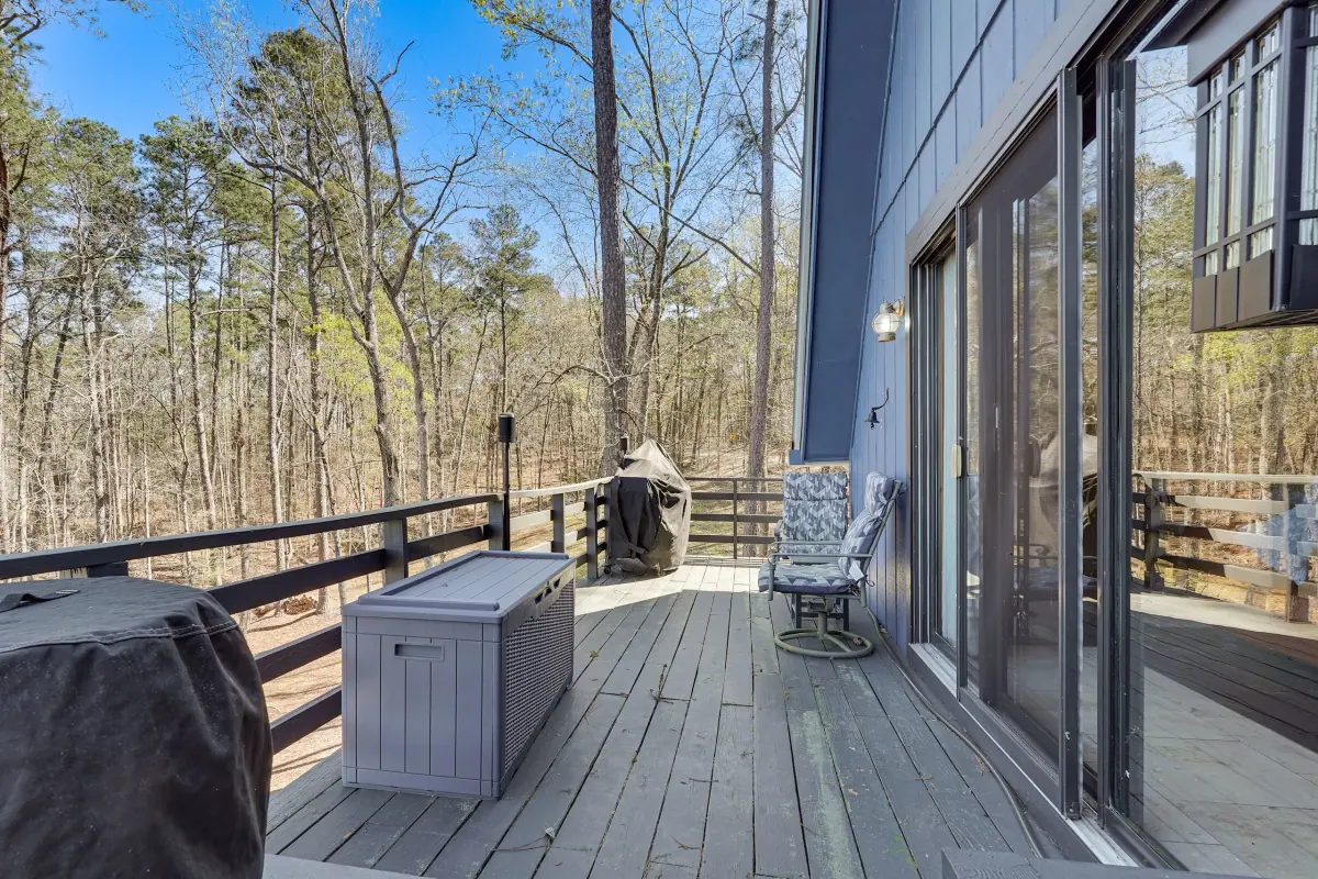 Deck with a fire table and seating beside the sliding doors, looking out through the pines.