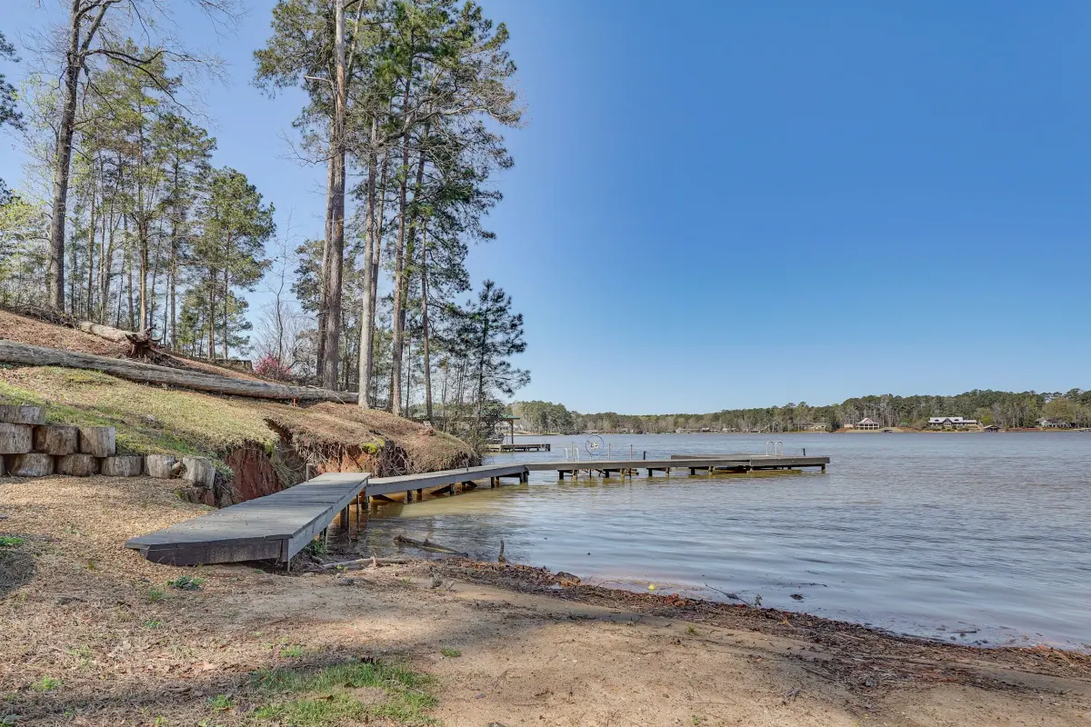 Wooden dock reaching out from a sandy shoreline into the open water of Lake Sinclair.