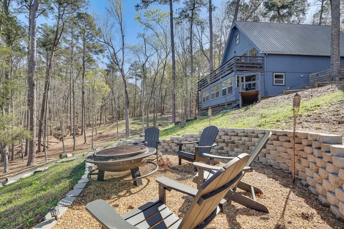 Fire pit ringed by Adirondack chairs on the terraced slope between the cabin and the water.