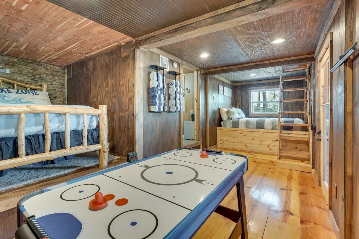 Lower-level room with an air hockey table in front of timber bunk beds.