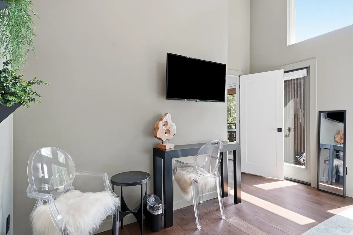 Bedroom with a mounted television, seating and a mirrored wardrobe.