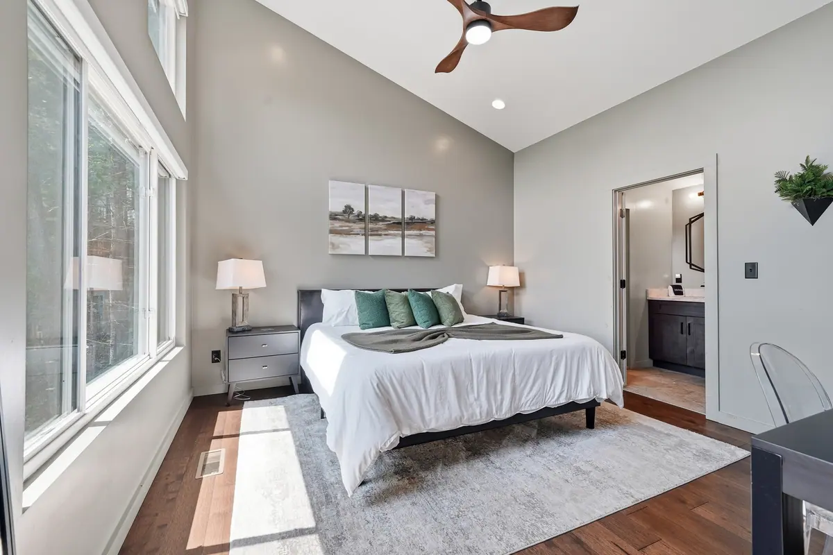 Bedroom with a king bed, soft neutral bedding and an adjoining bathroom.