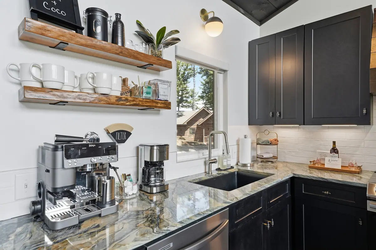 Kitchen with dark cabinetry, open timber shelving and a barista coffee machine on the counter.
