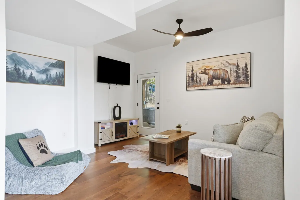 Lower-level living room with a sectional sofa, mounted television and framed mountain artwork.