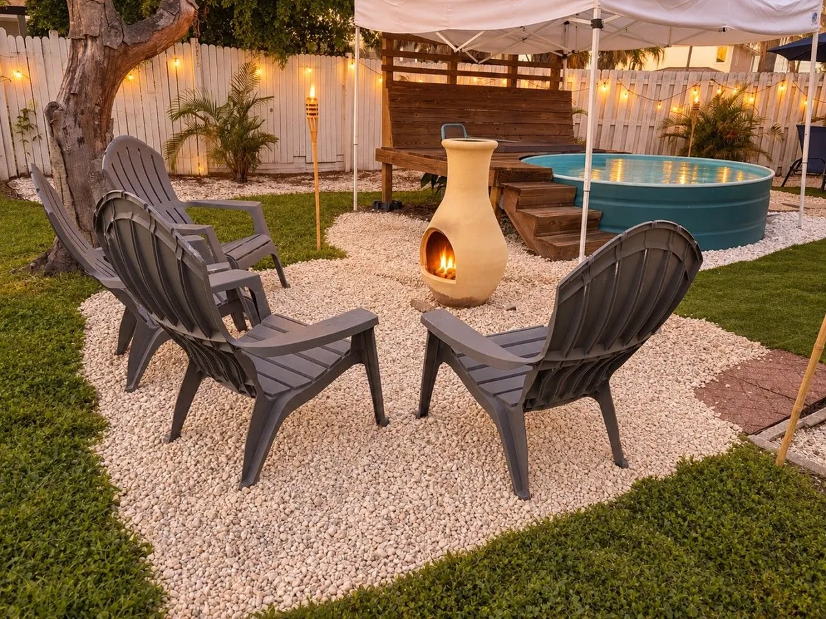 Nonna’s Beach Haus backyard with Adirondack chairs around a lit chiminea and a turquoise plunge pool.