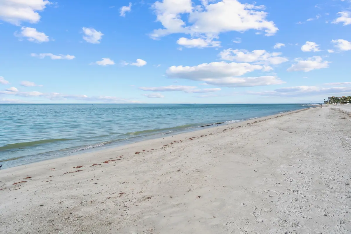 The broad white-sand beach at Redington Beach with calm Gulf water and a clear sky.