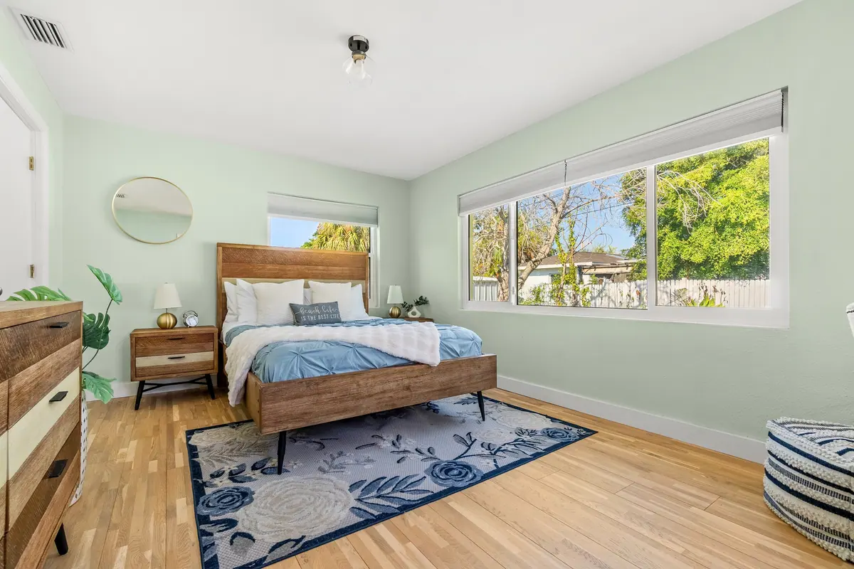 Bedroom with a timber bed frame, blue bedding and a large window looking onto the garden.