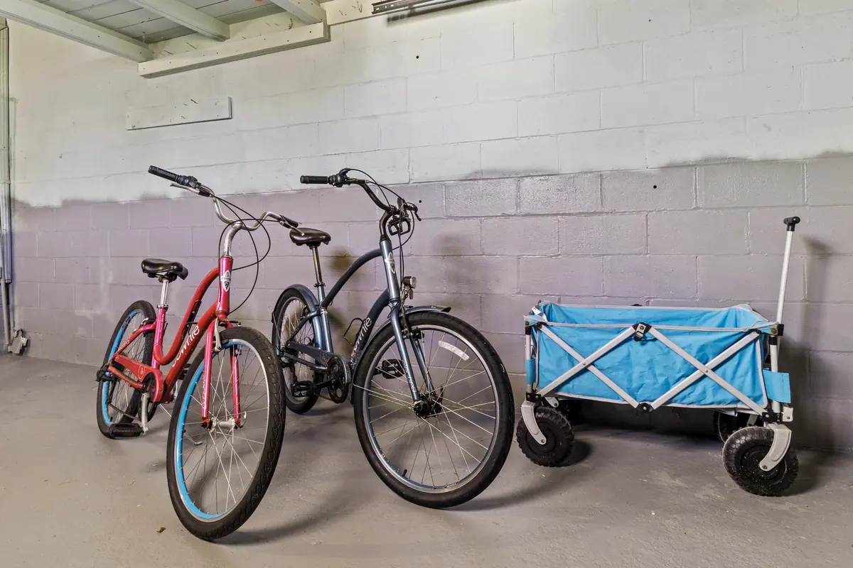 Two cruiser bicycles and a folding beach wagon parked in the garage, ready for the walk to the sand.
