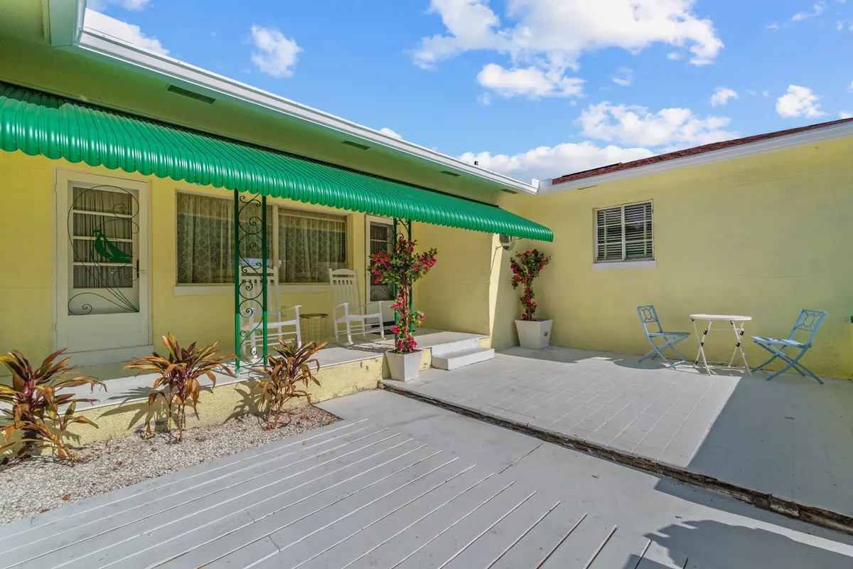 Raised deck along the back of the cottage under a green awning, with potted plants and seating.