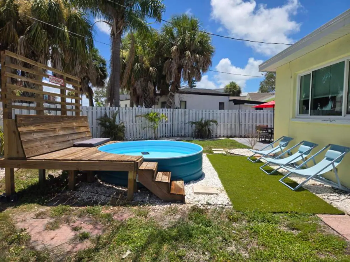 The plunge pool and sun deck seen from across the lawn, with loungers lined up along the fence.