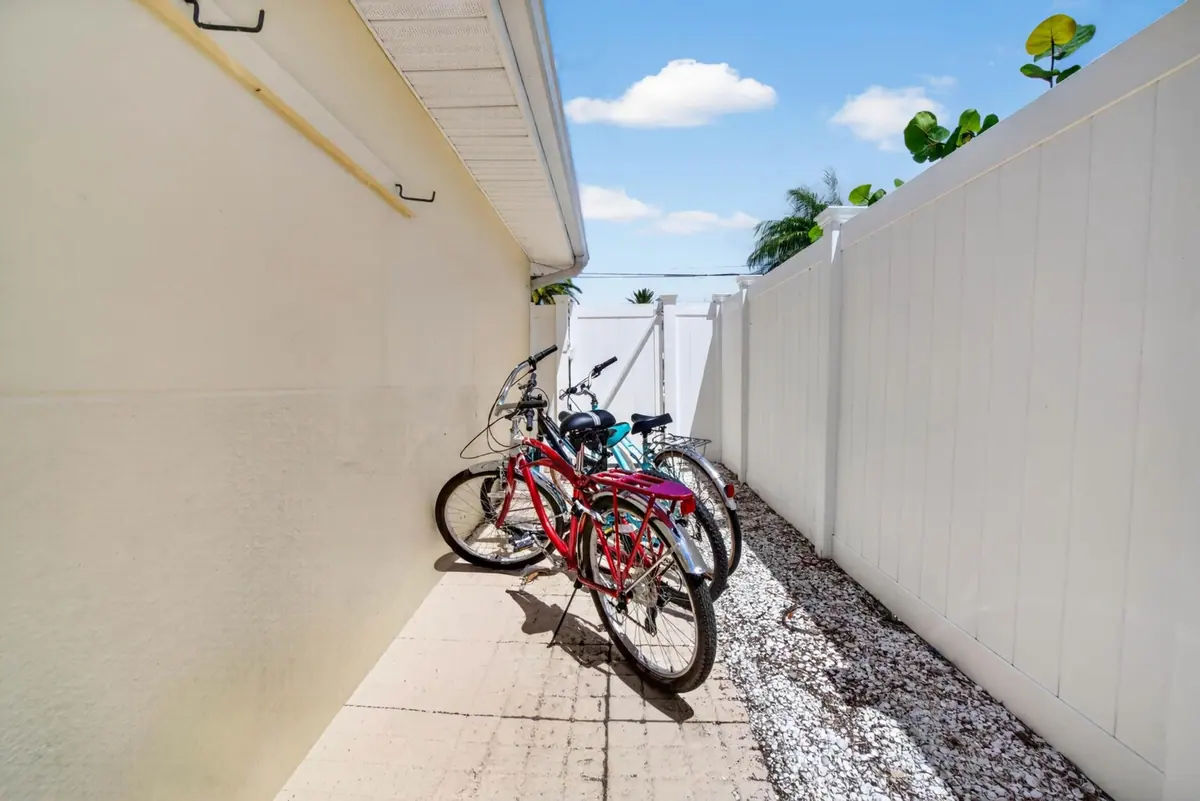Two cruiser bicycles parked along the side path of the house, ready for the ride to the beach.