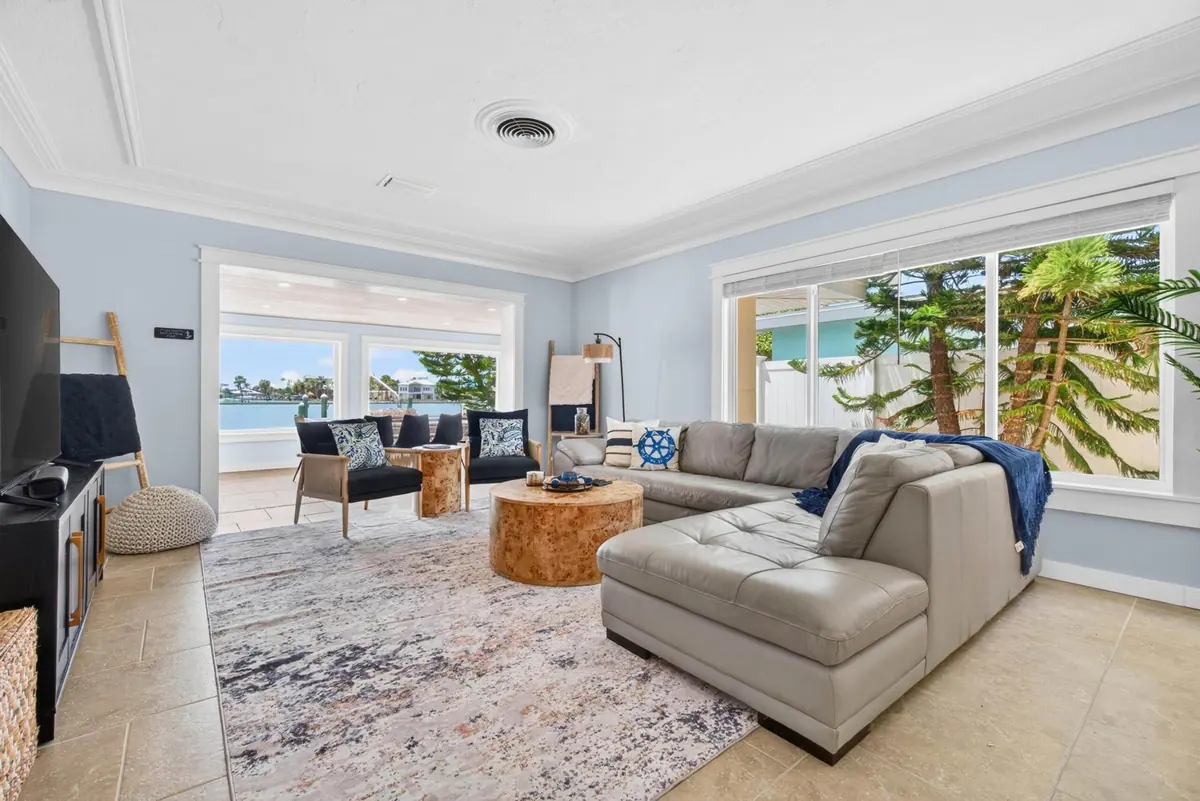 Bright living room in pale coastal blue with a deep sectional sofa and windows framing the palms outside.