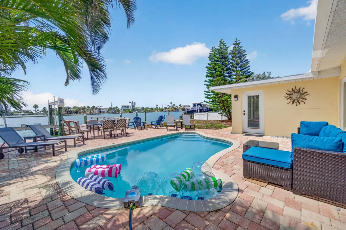 The pool and sun loungers seen from the water’s edge, with the cove and the far shoreline stretching out behind.