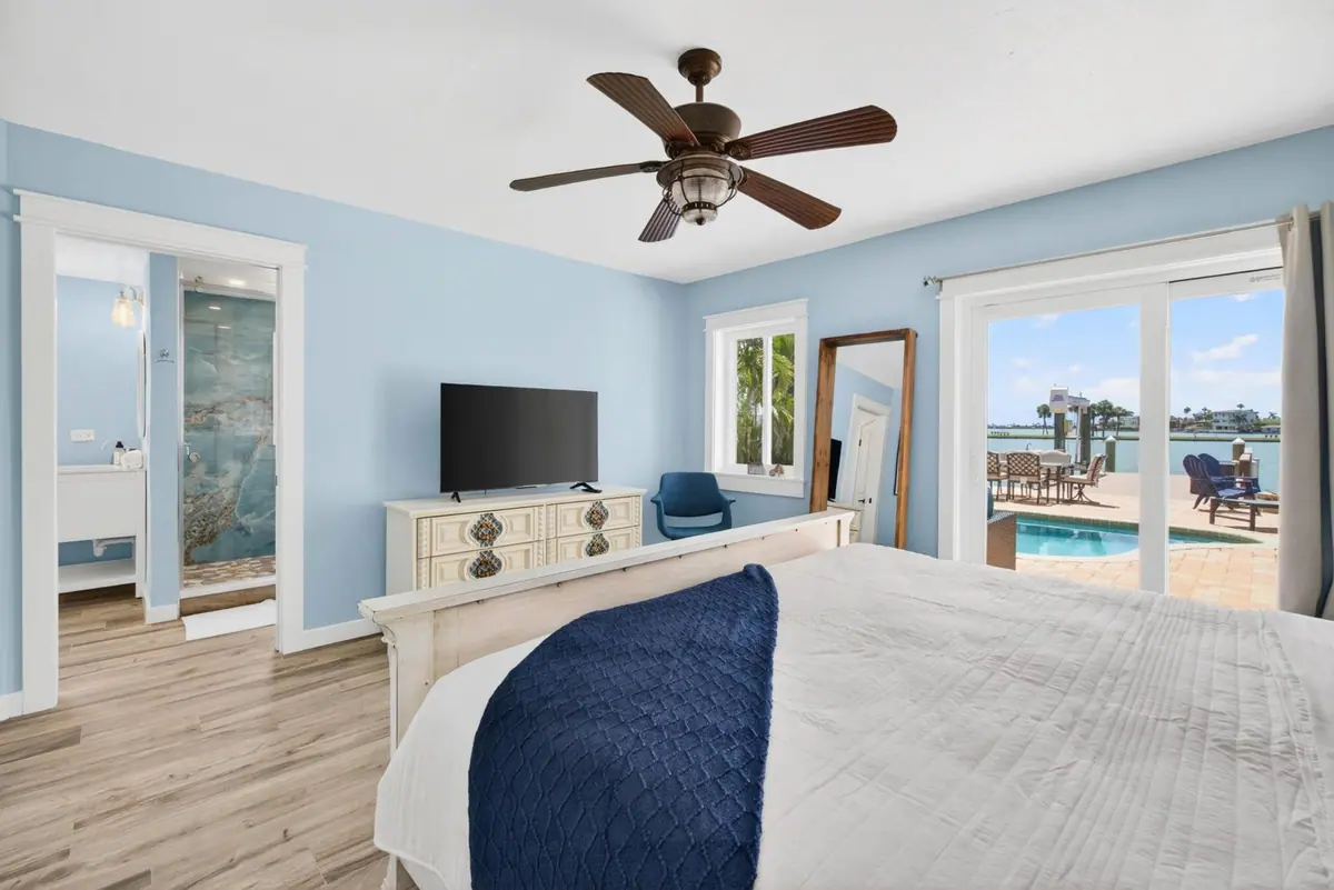Primary suite with a king bed, a wall of glass to the patio and the pool visible beyond.