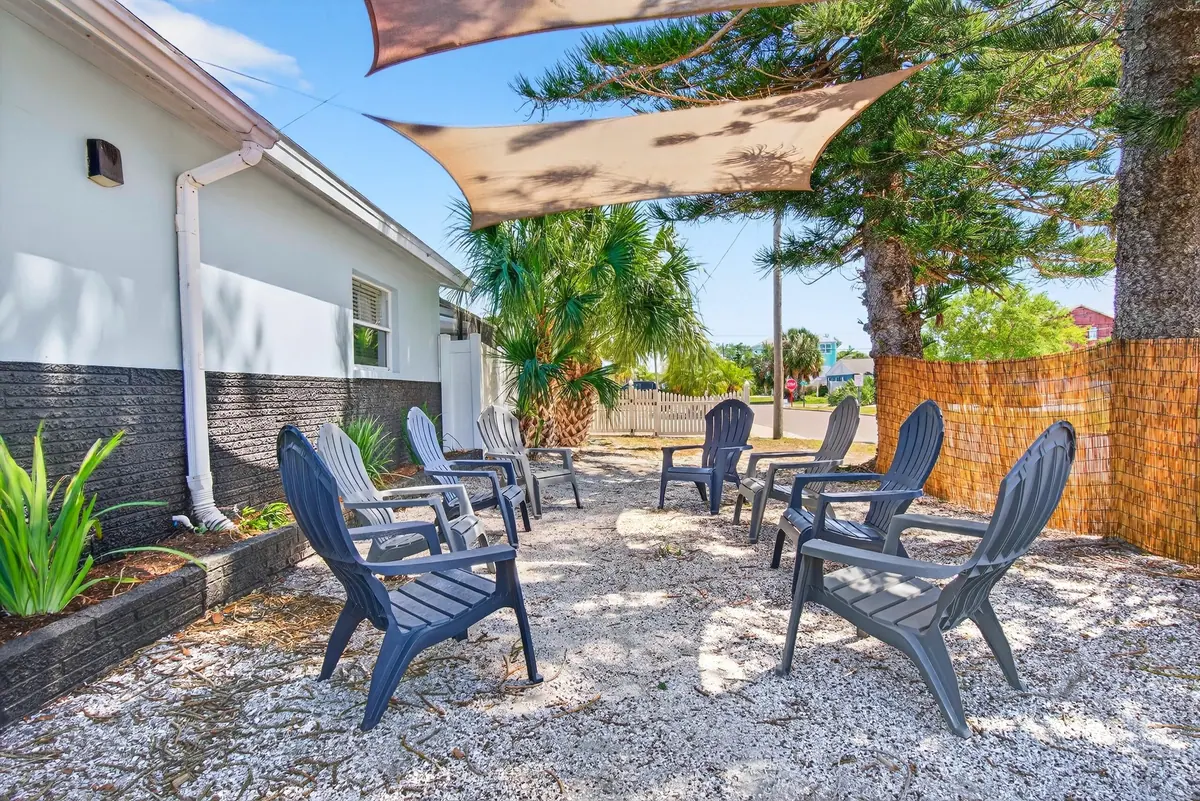 Adirondack chairs arranged on the shell-covered backyard beneath triangular shade sails.