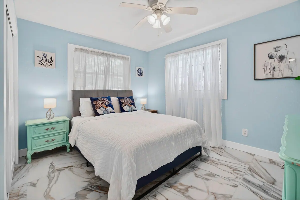 Queen bedroom with mint-green bedside tables and soft white bedding.